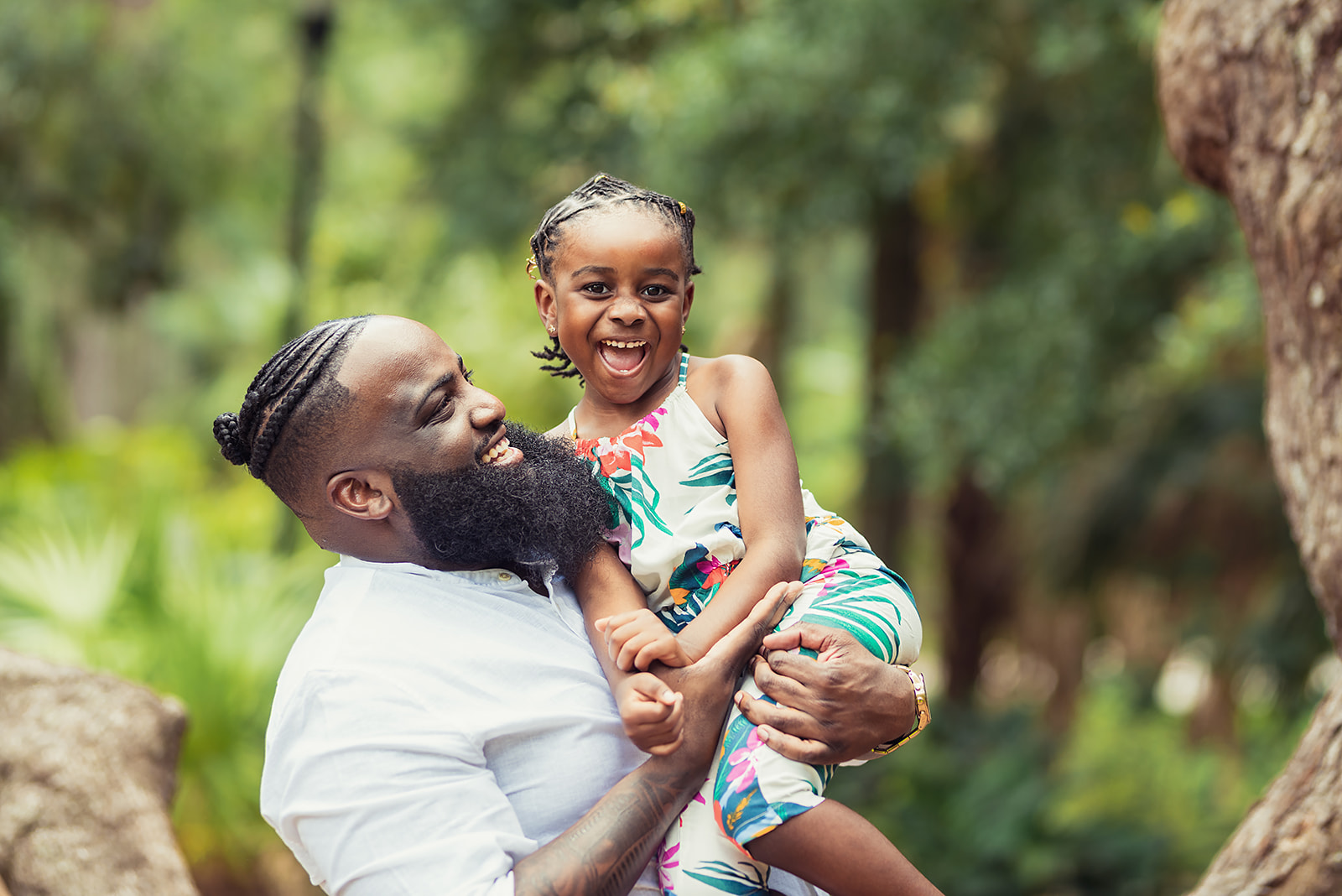Dad lifting his laughing daughter in the air during a Father's Day portrait session