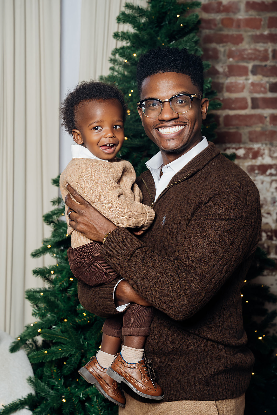 New dad holding his toddler son in a warmly lit studio session