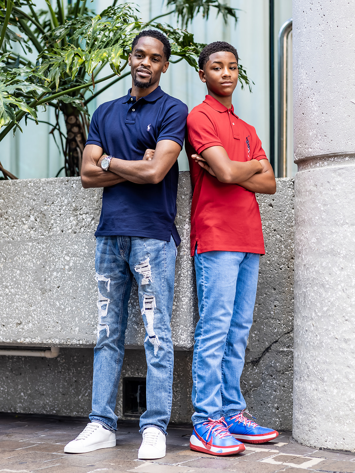 Father and teenage son standing back-to-back in matching polos for a father-and-son portrait